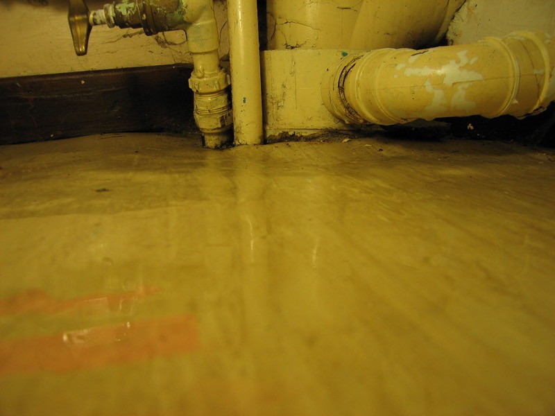 Water pooled on the floor beneath the refrigerator